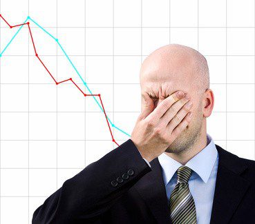 Bald man with palm on face with graph on the background